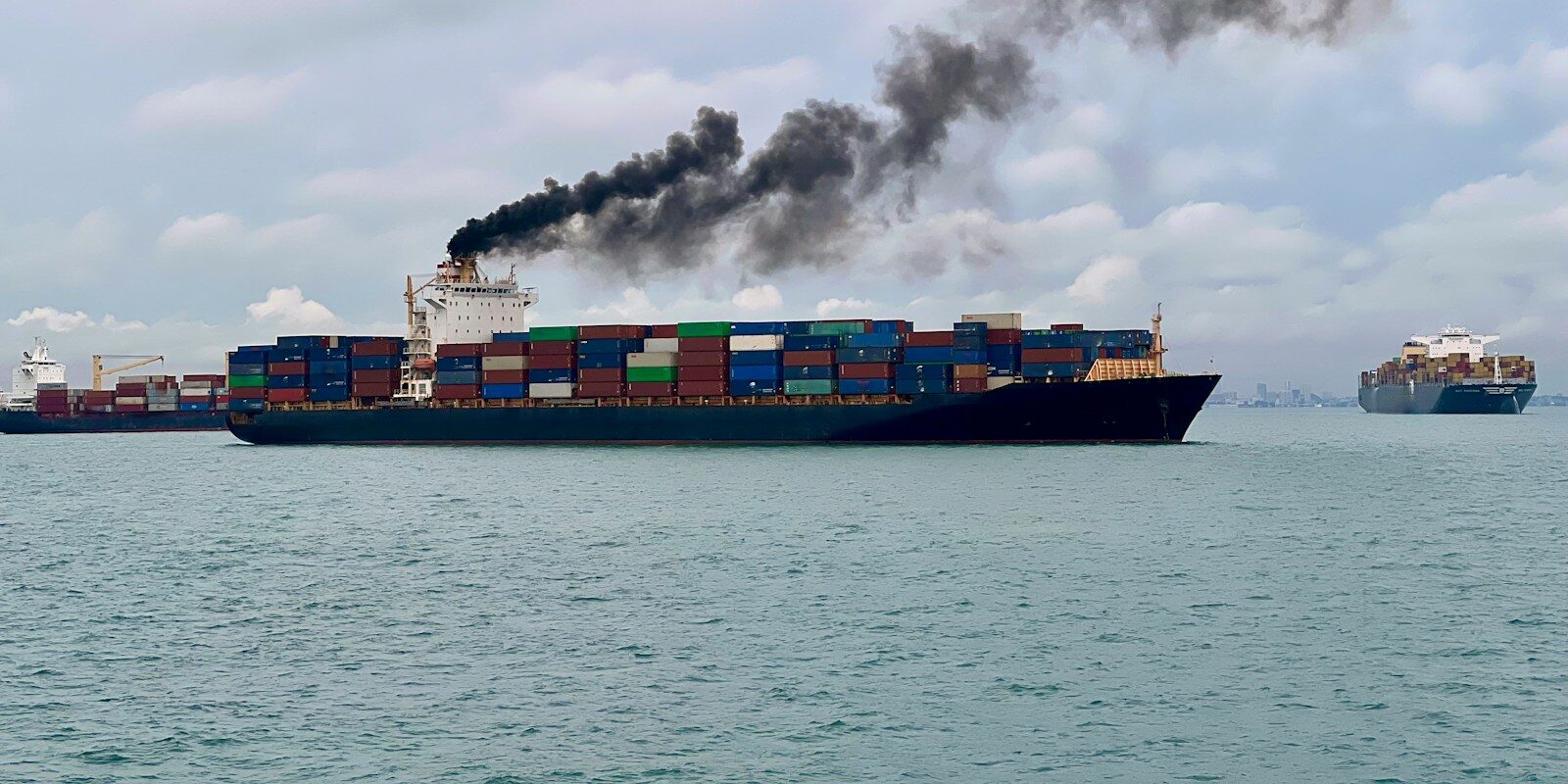 a large cargo ship with a lot of smoke coming out of it